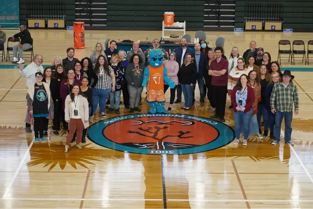 faculty members gathered together in the gym around the fighting cacti mascot